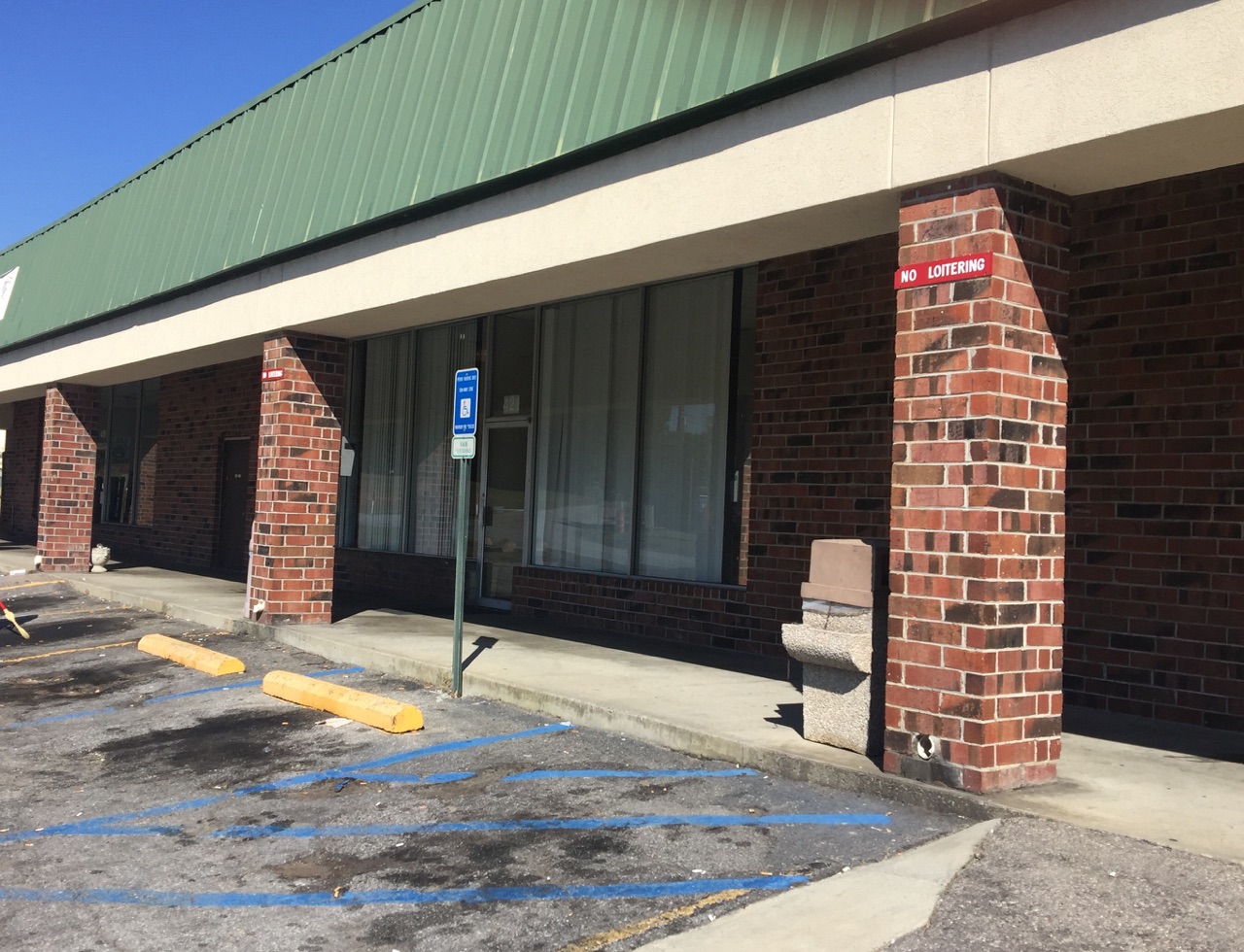 A brick rehab facility in a strip mall with parking spaces and signage.