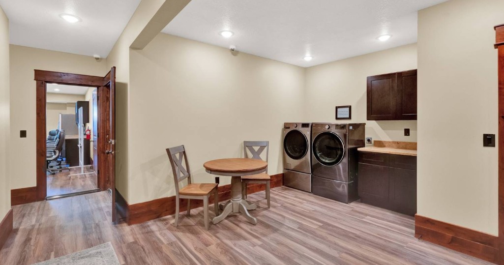 Laundry room with washers, dryers, cabinetry, and seating area
