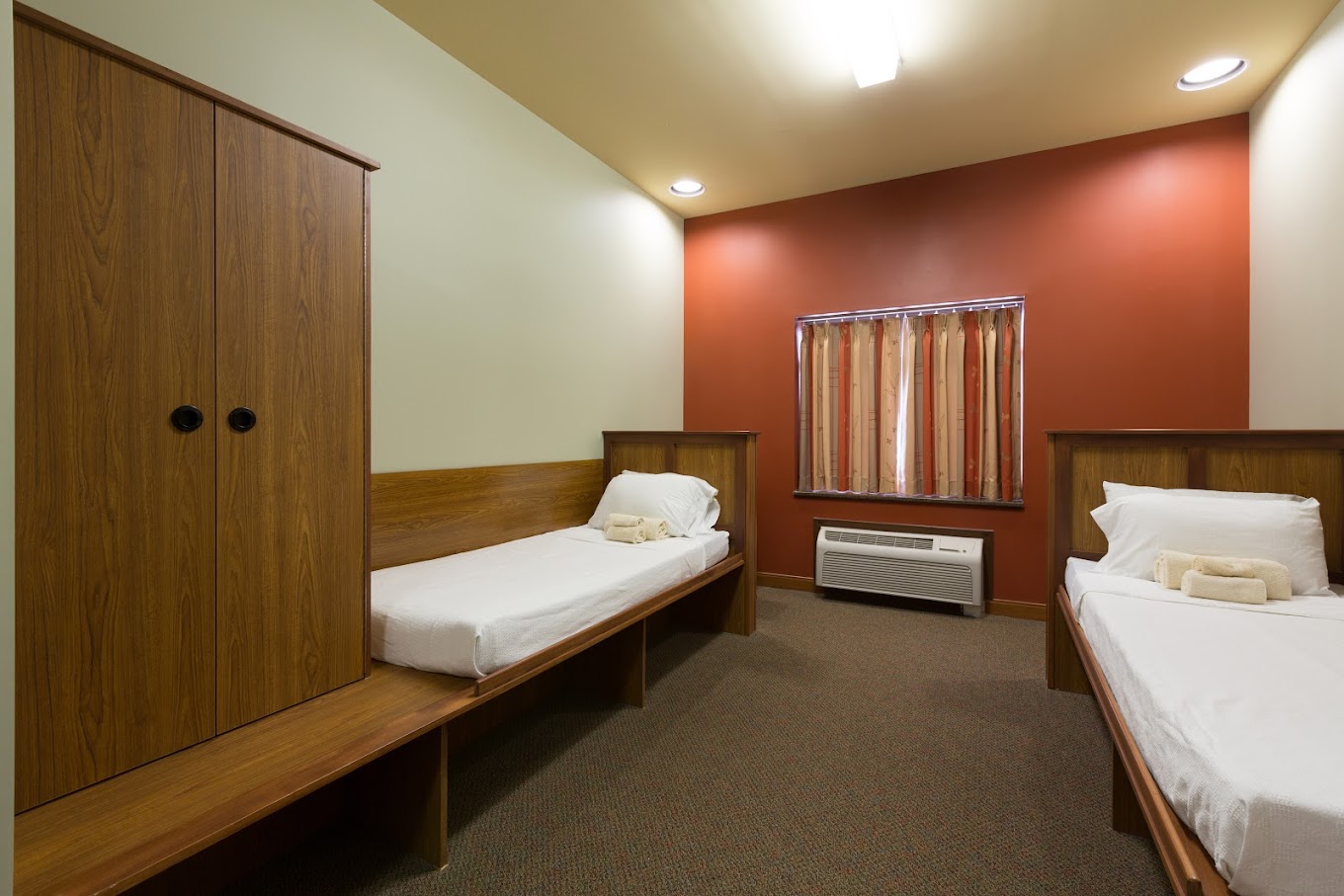 Two-bed rehab bedroom with wood furniture and soft lighting