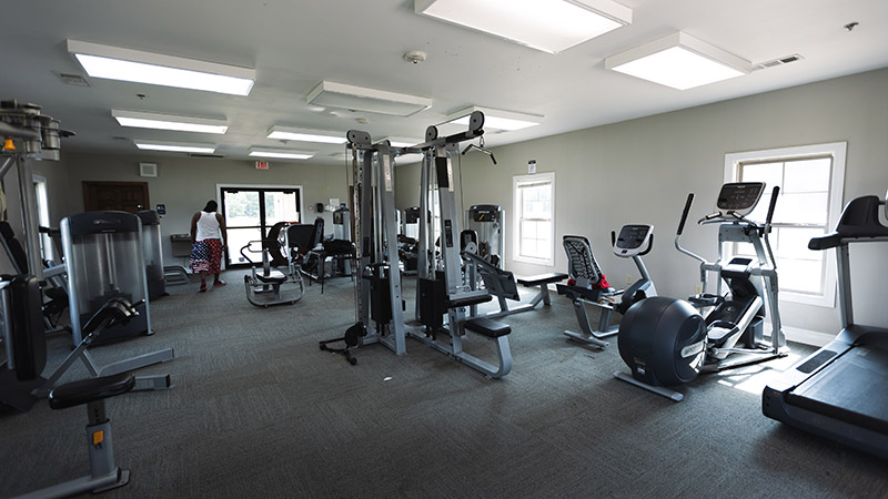 Fitness room with exercise machines, cardio equipment, and a person near the exit door