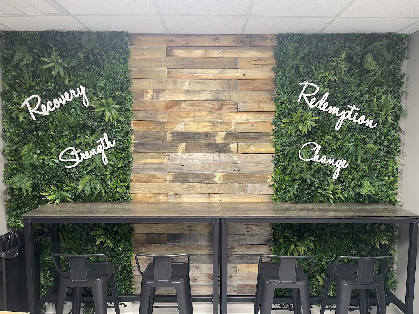 A decorative wall with greenery and words: Recovery, Strength, Change.