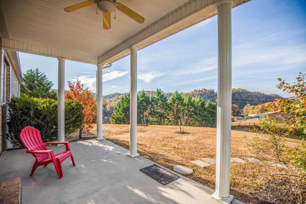 Covered porch with red chair overlooking grassy yard and trees