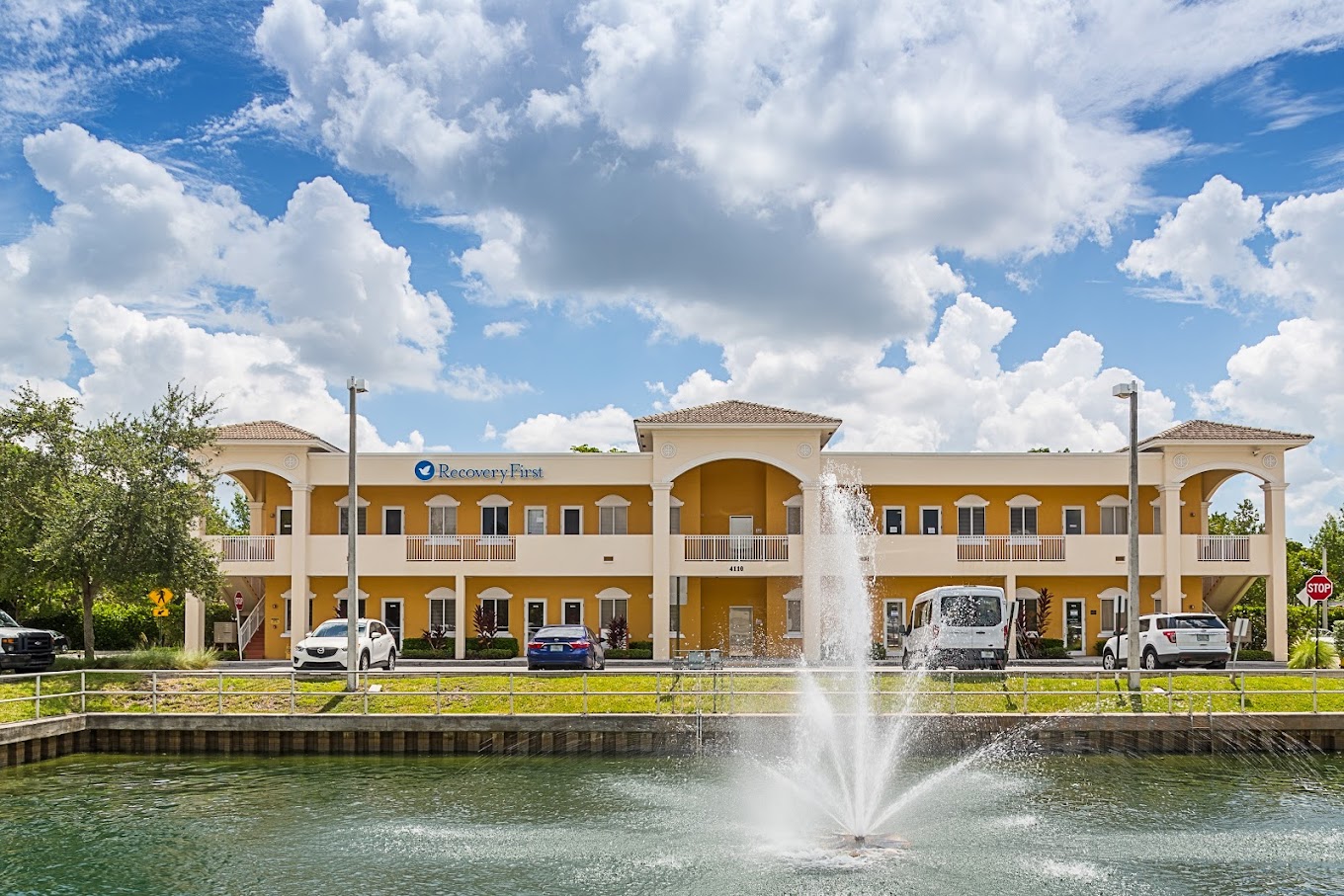 Two-story treatment facility with a fountain and parking area.
