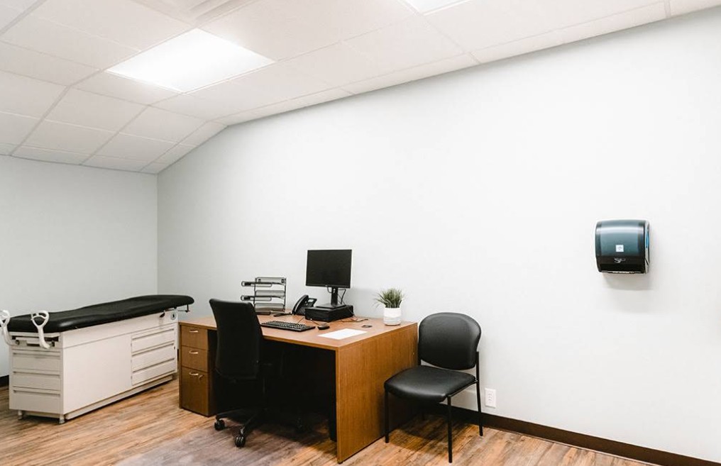 Exam room with desk, chair, and exam table