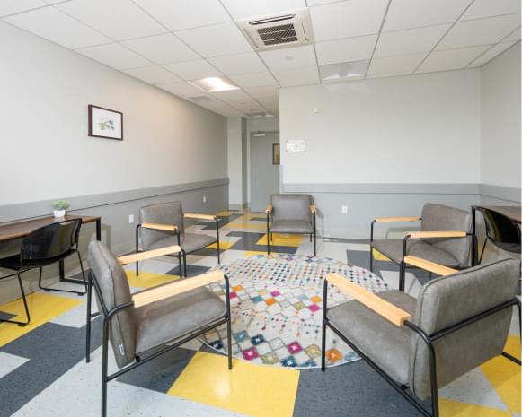 Modern group therapy room with gray chairs and colorful rug