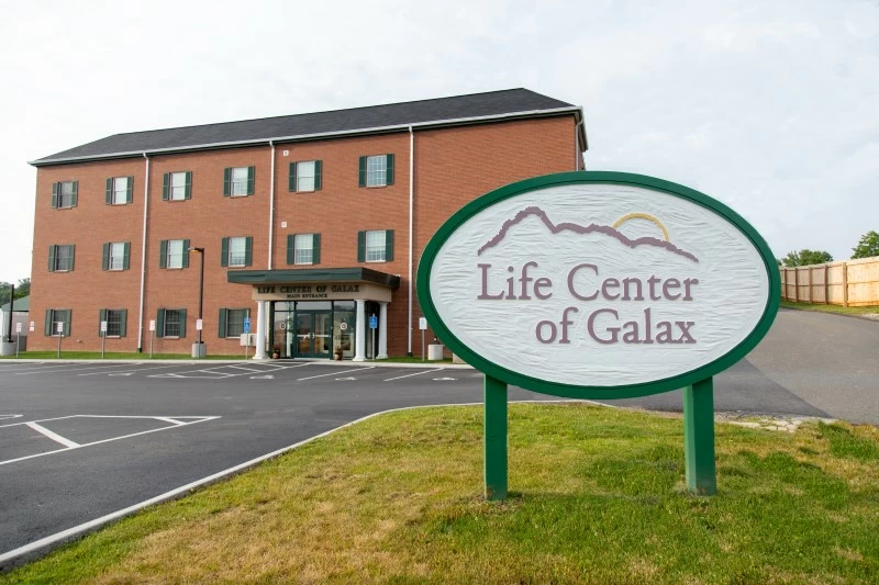 Brick rehab facility with entrance sign and parking