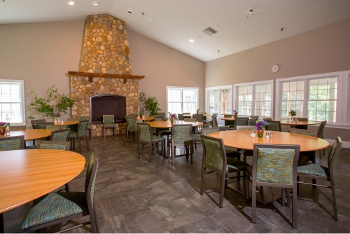 A dining area with round tables, chairs, and a stone fireplace.