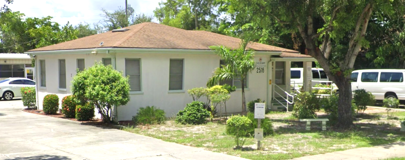 Side view of white residential facility with driveway and trees
