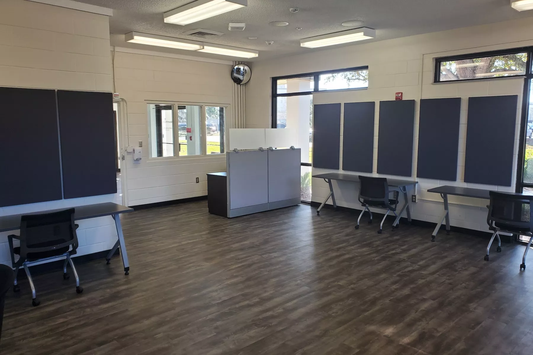Group room with tables, chairs, wood flooring, and windows