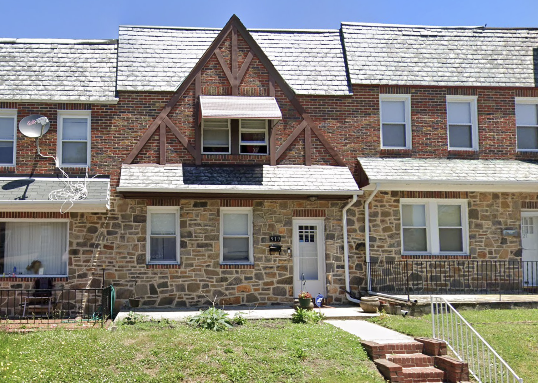 Two-story brick and stone house with front lawn and walkway