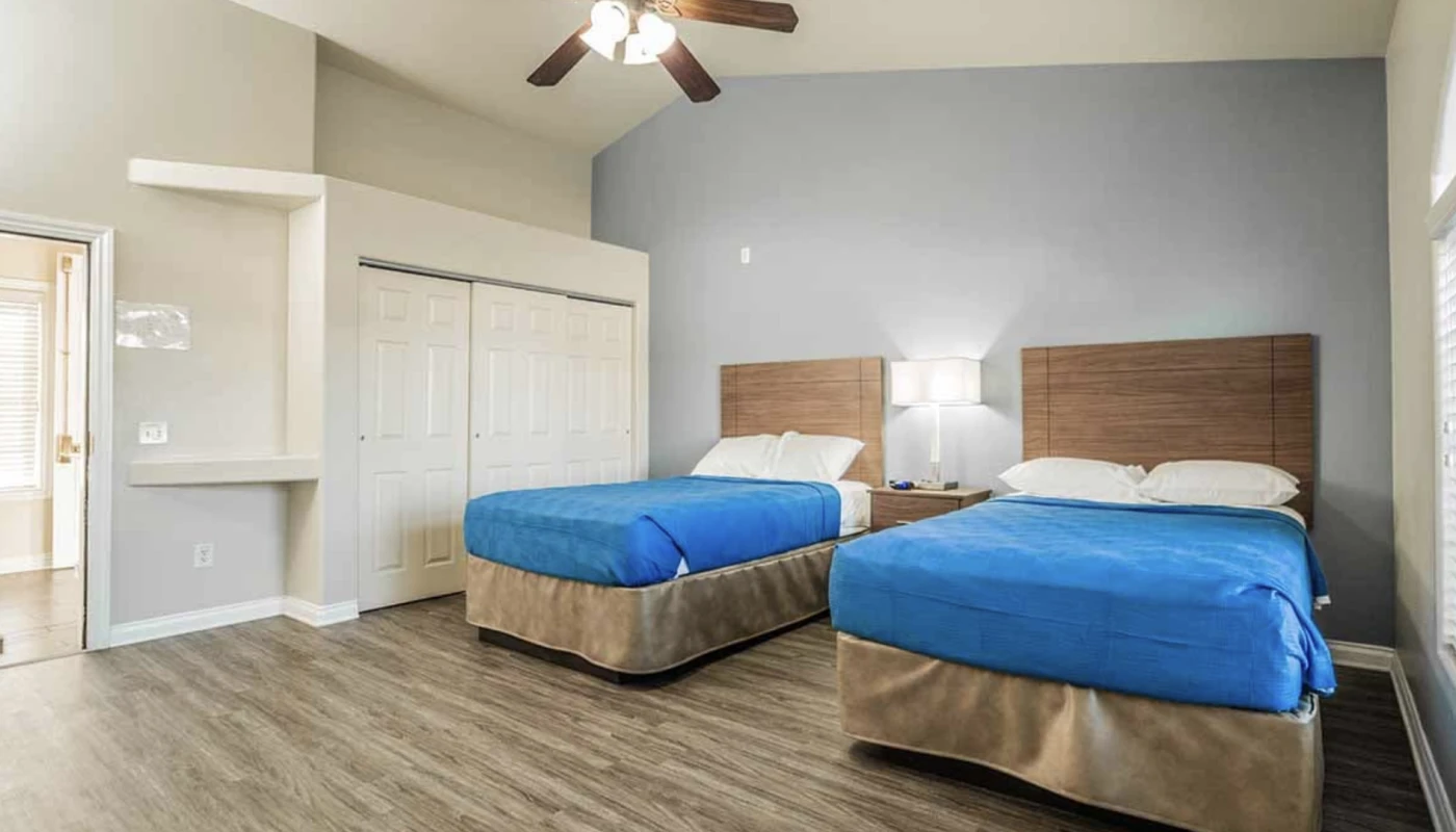 Two-bed client room with blue covers and soft lighting