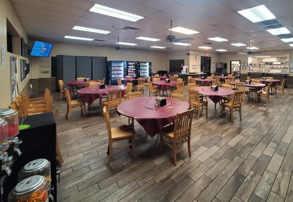 Dining hall with round tables, vending machines, and serving counter