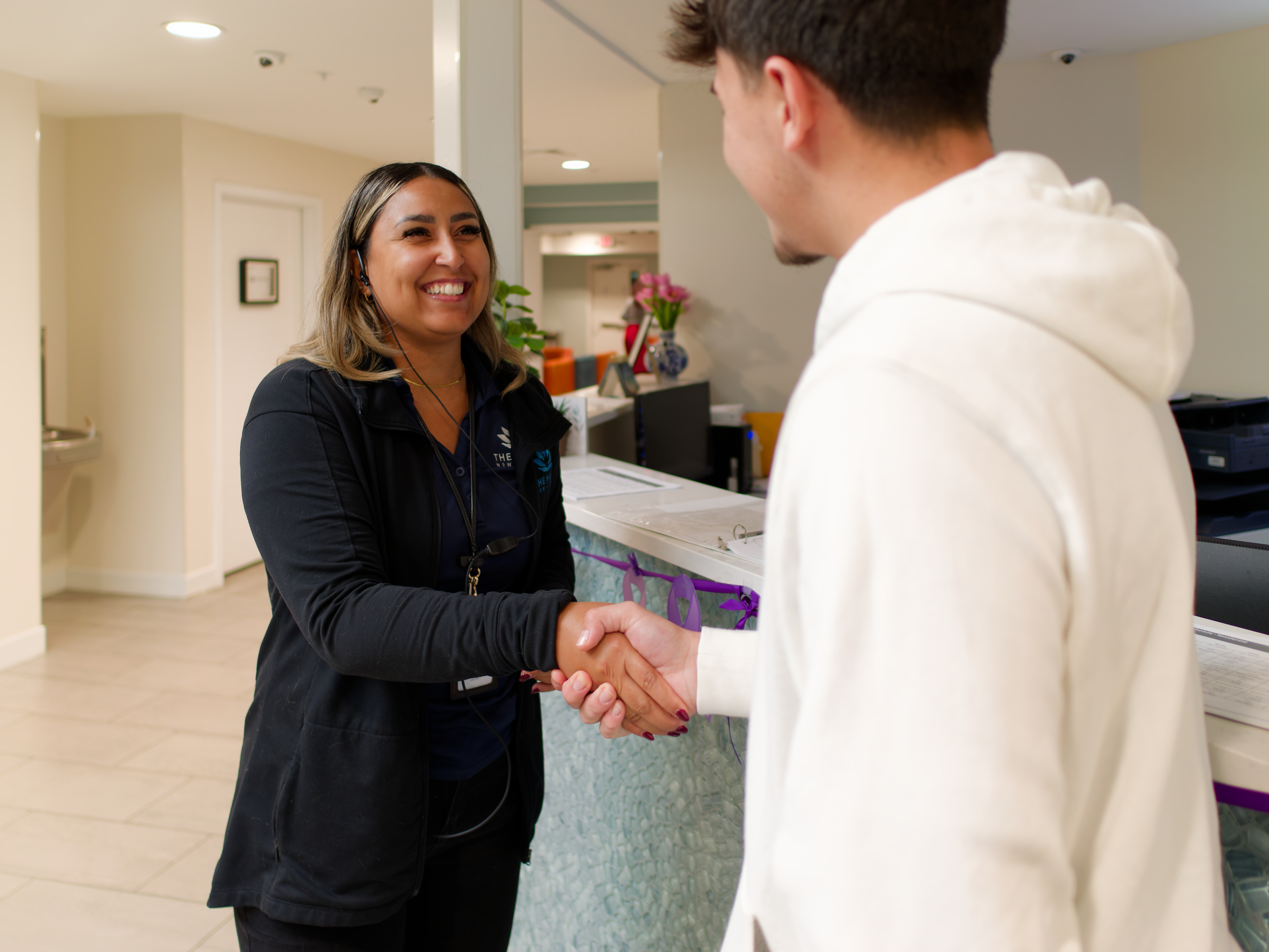 Staff member greeting and shaking hands with a new arrival.