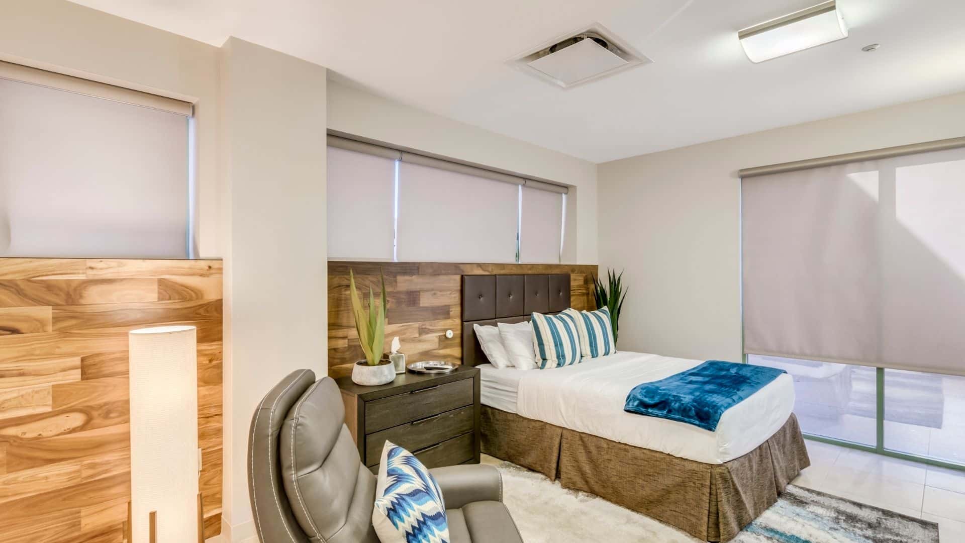Bedroom with a made bed , an armchair, and a side-table.