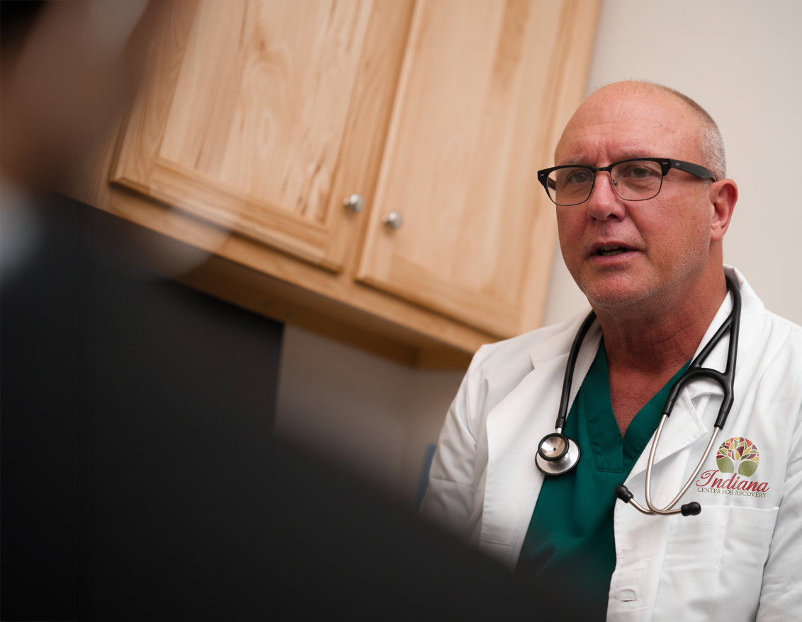Doctor with stethoscope speaking during consultation.