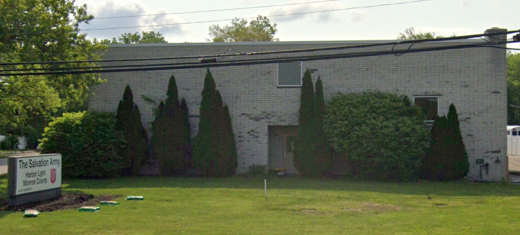  A light-colored building with neatly trimmed bushes and large trees providing a serene atmosphere.