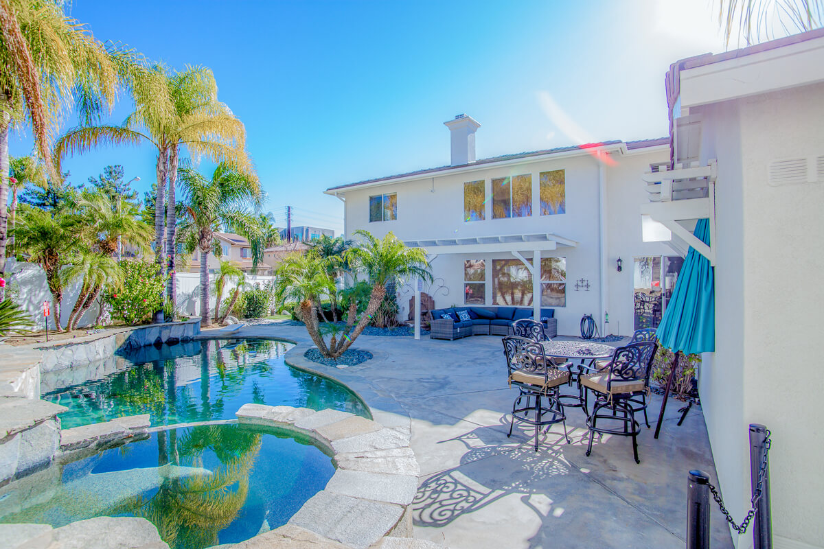Backyard with a pool, palm trees, and patio seating