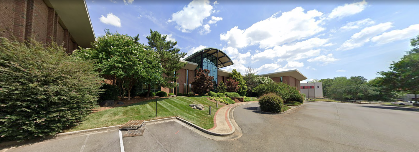 Facility exterior with driveway and trimmed green lawn
