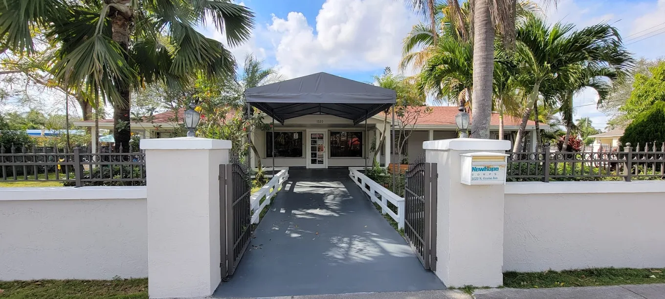 Front entrance of New Hope CORPS with canopy walkway and palm trees.
