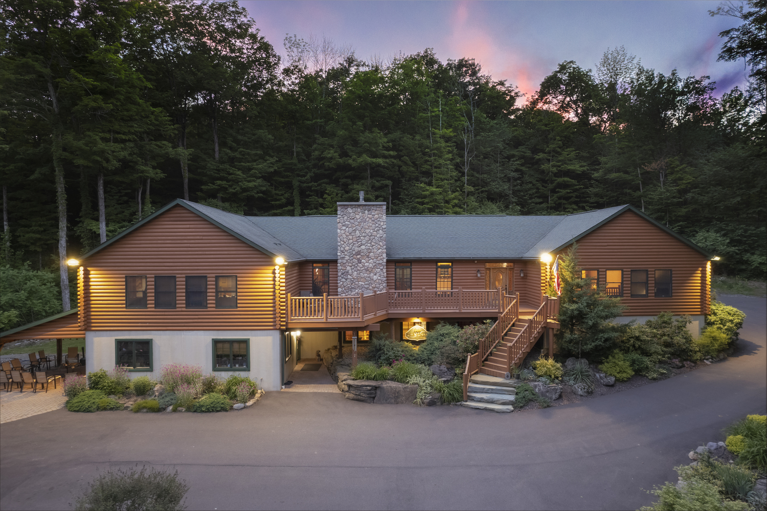 A spacious wooden lodge with a stone chimney, lit at dusk
