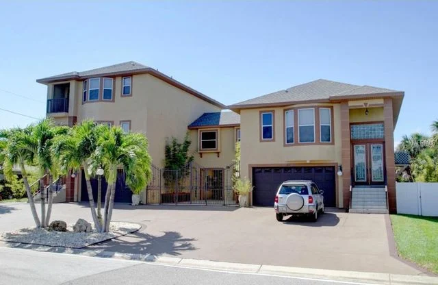 Large tan recovery home with palm trees and garage