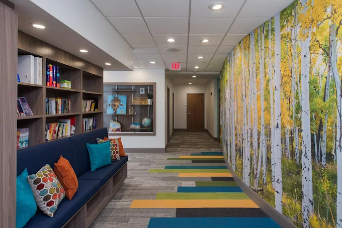 Hallway with bench seating, bookshelves, and forest mural