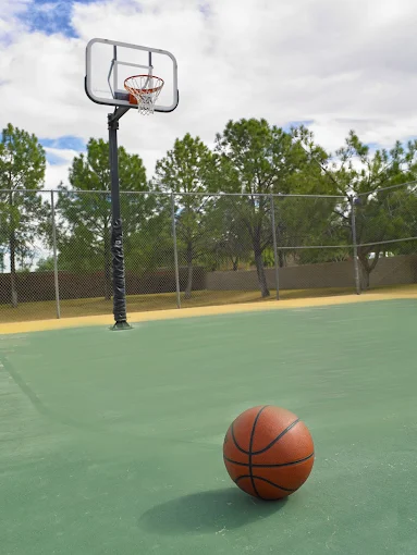 Basketball court with hoop and ball under blue sky