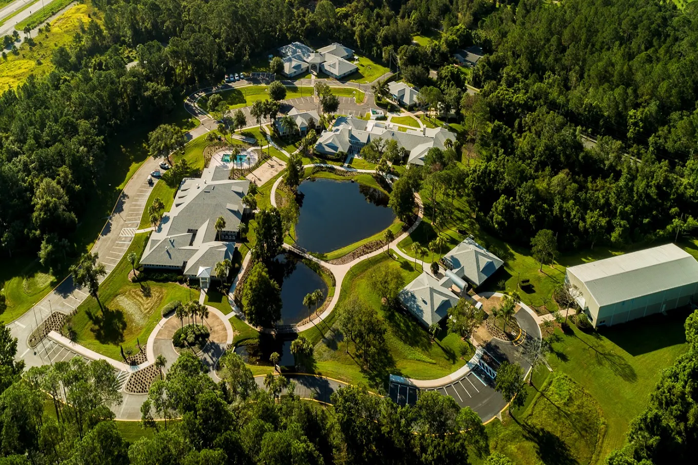 Aerial view of campus buildings, ponds, paths, and wooded grounds