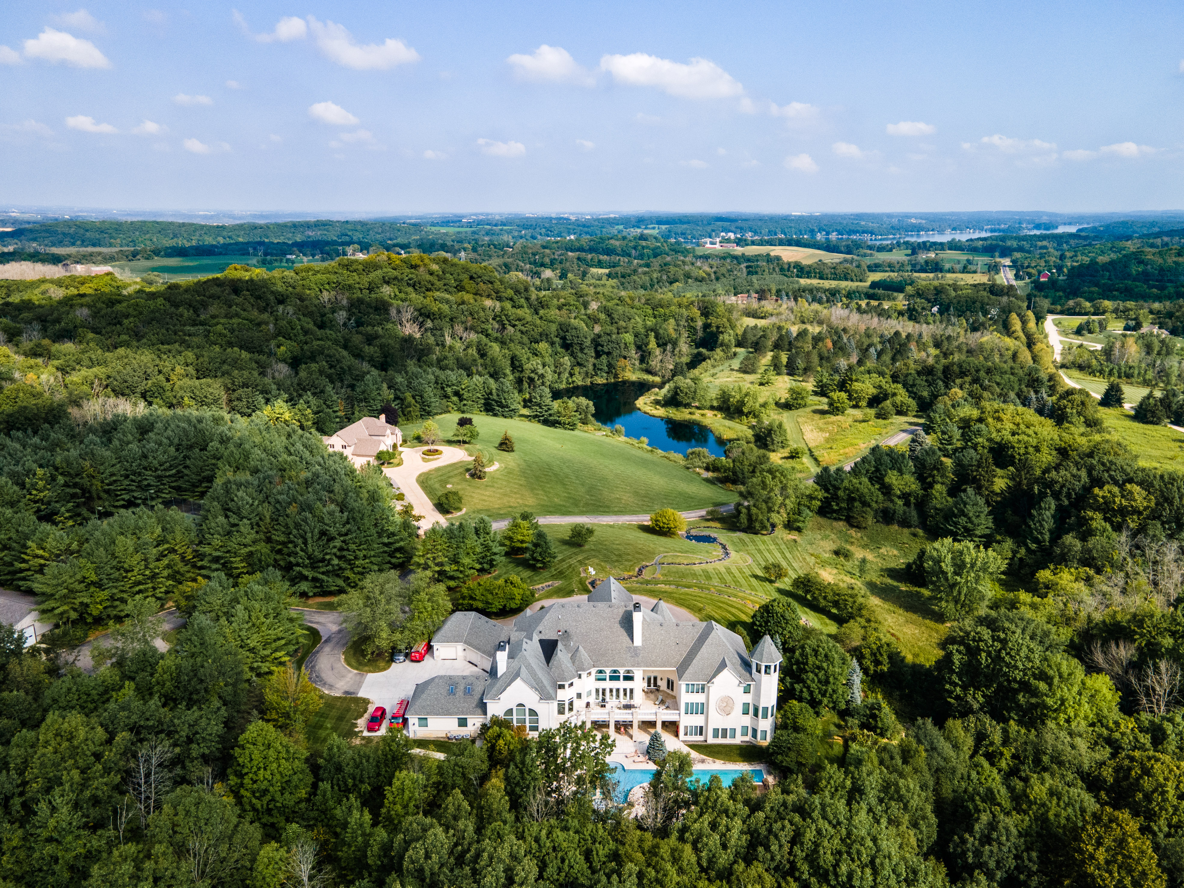Aerial view of large estate with landscaped lawns and lush trees.