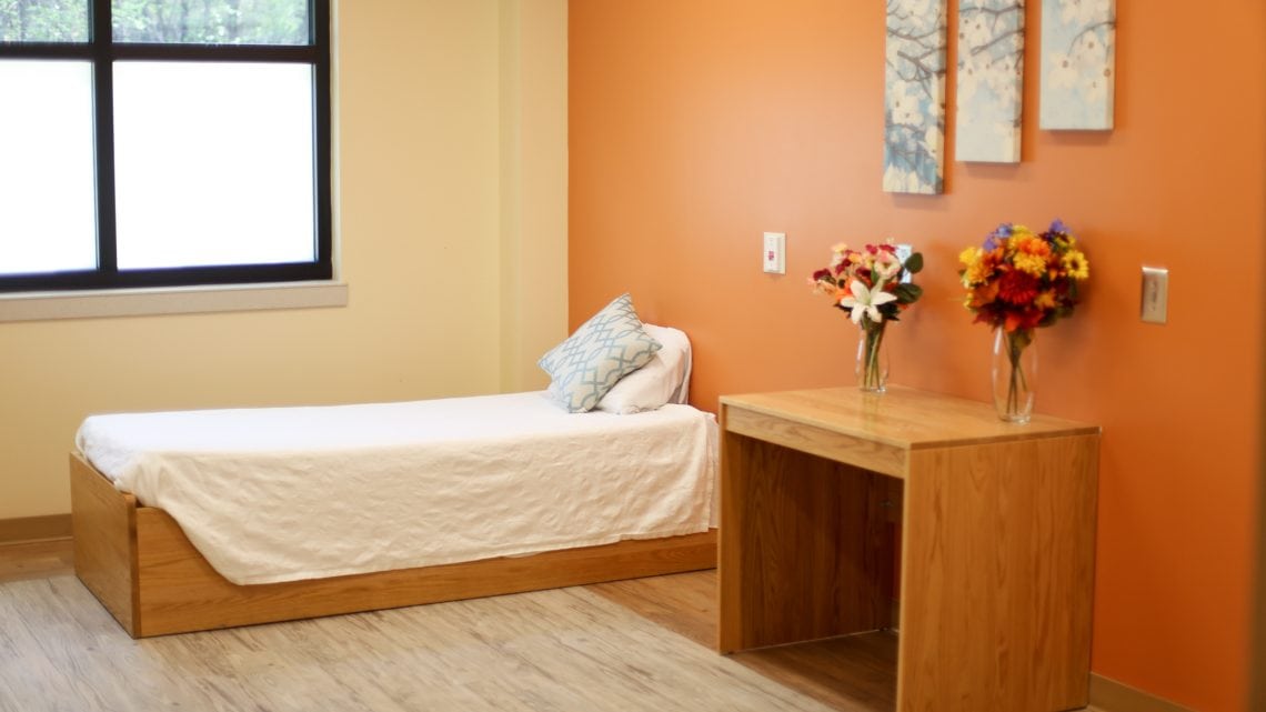 Single bed and desk with orange accent wall