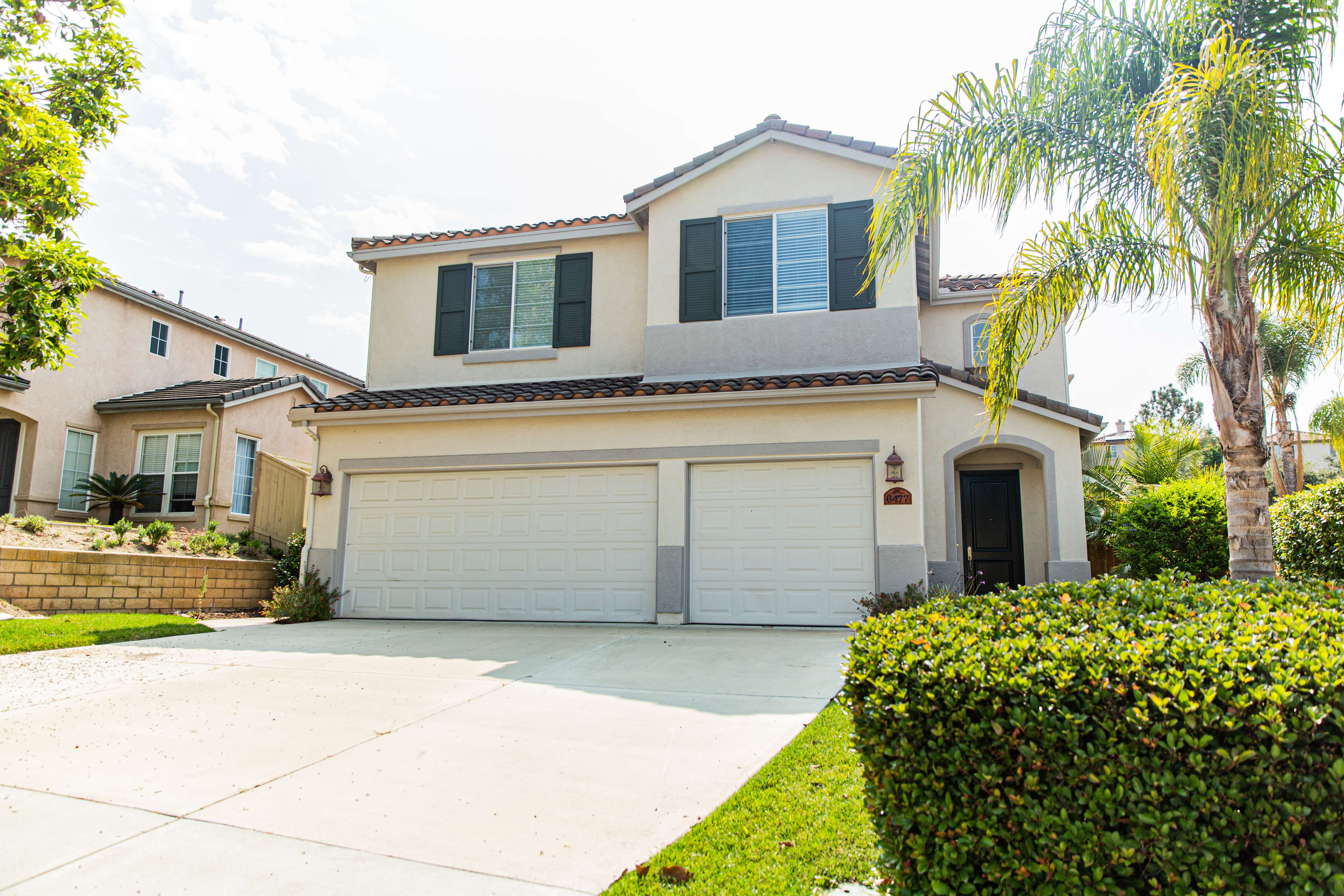 Two-story house with a large driveway and palm tree