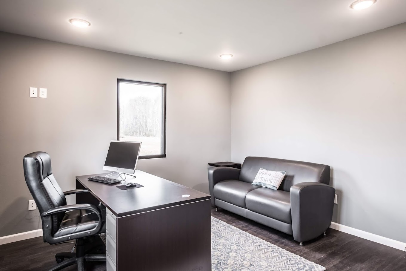 Small office with black desk, computer, and leather couch