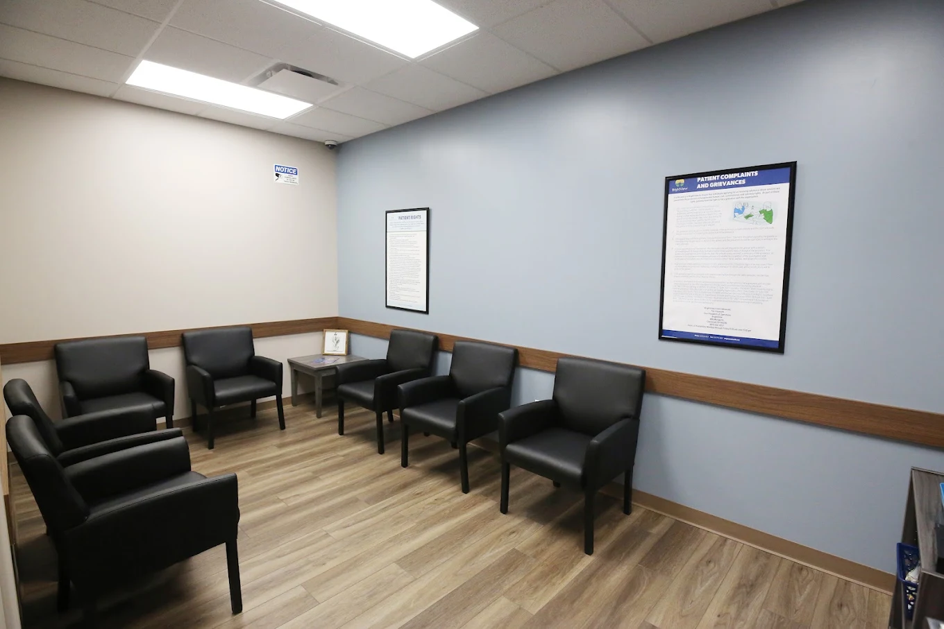 BrightView Elyria waiting room with black chairs, blue accent wall, and patient information posters
