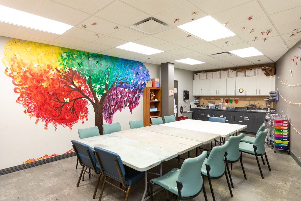 Art therapy room with mural, tables, and creative supplies