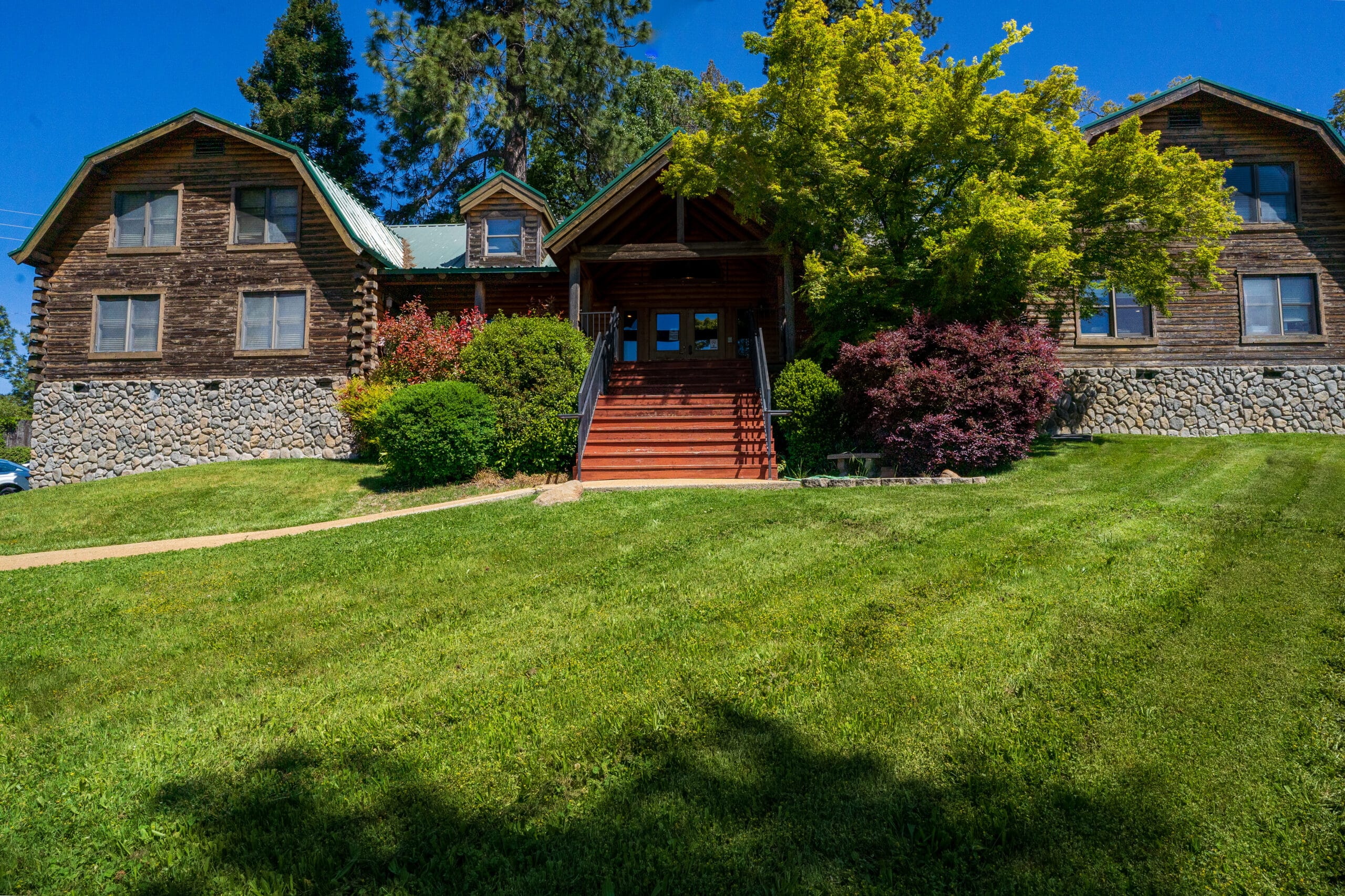 Covered patio with red-cushioned chairs and a glass table, offering a peaceful view of trees and natural surroundings