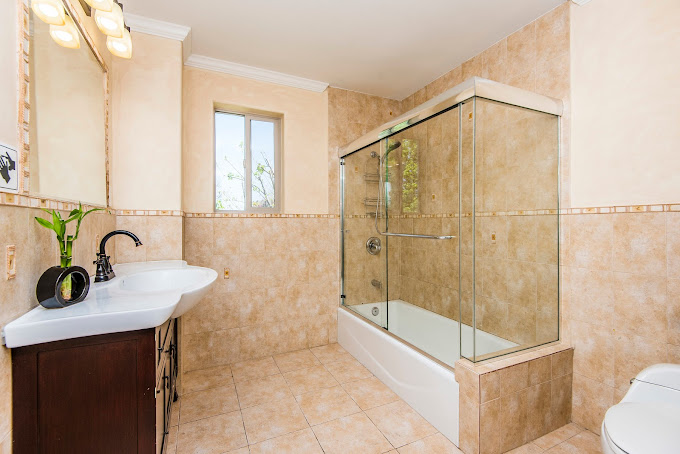 A bathroom with a glass-enclosed shower and warm tile design.