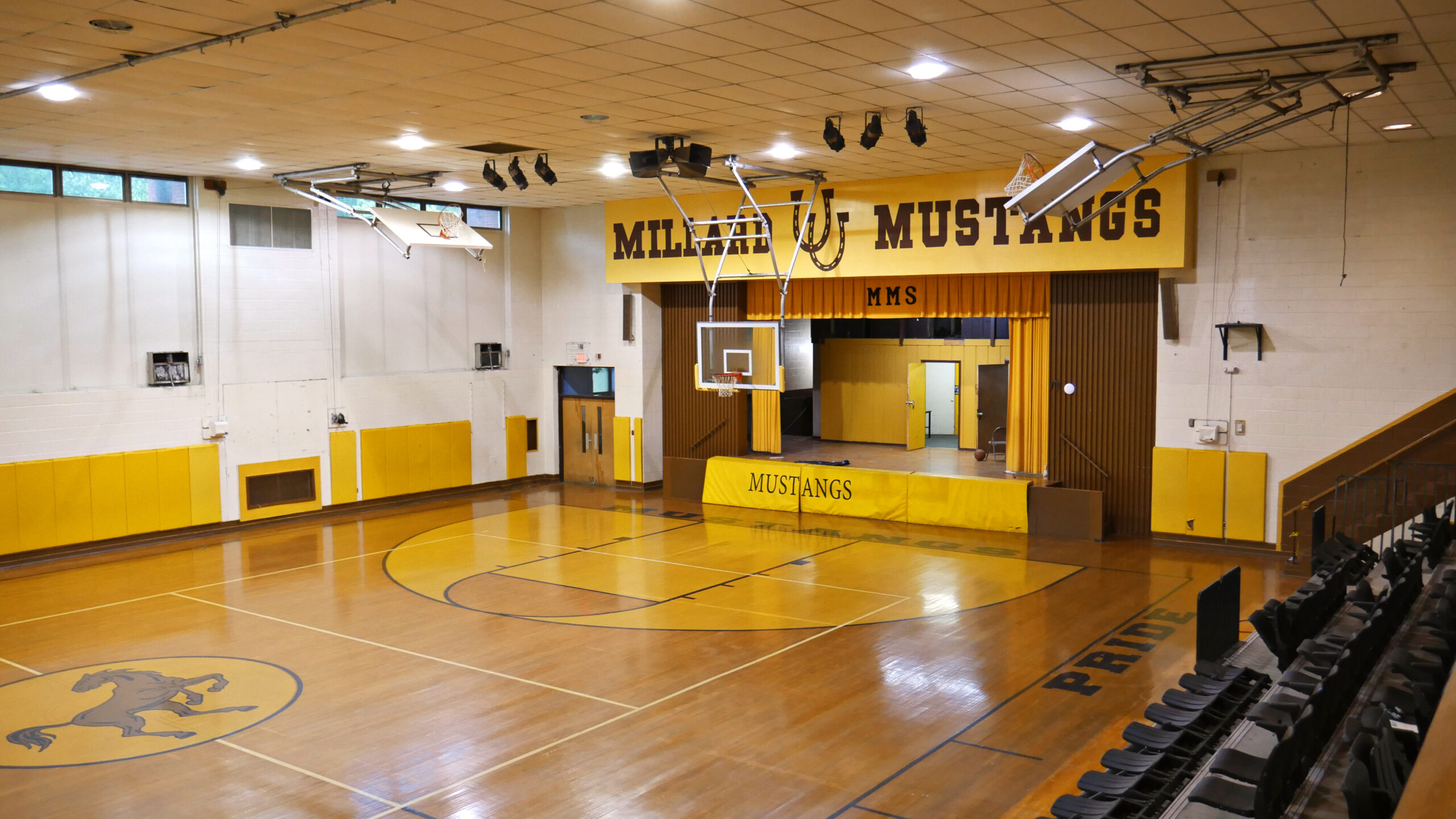 Full indoor basketball court with yellow bleachers