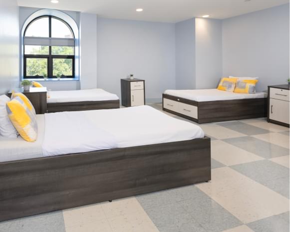 Bright room with three beds, checkered flooring, and large window