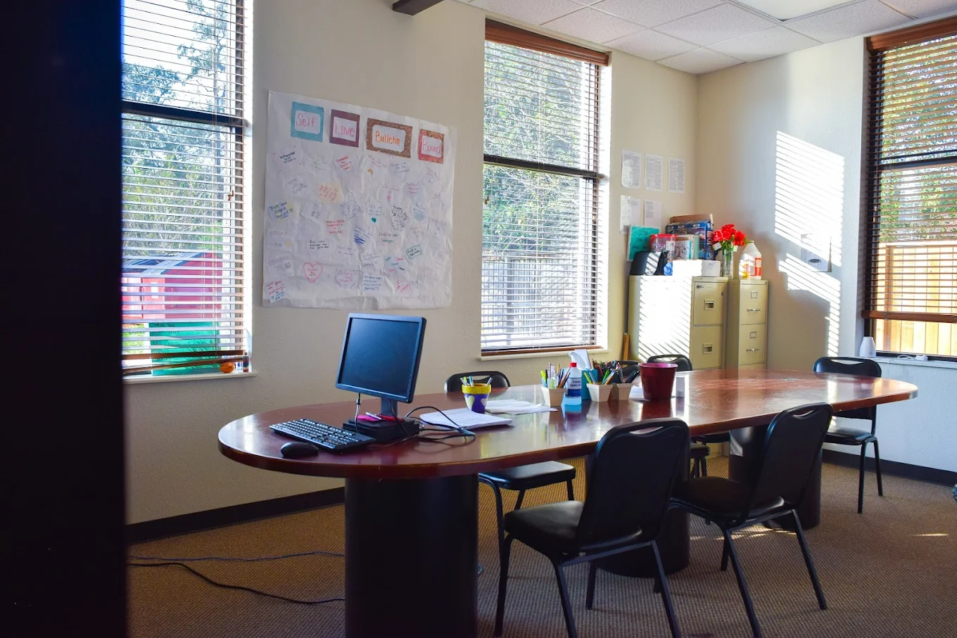 Office table with computer, chairs, and art bulletin board