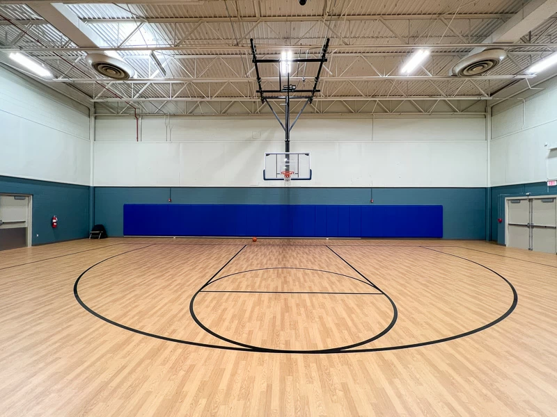 Indoor basketball court with full-size hoop and wood flooring