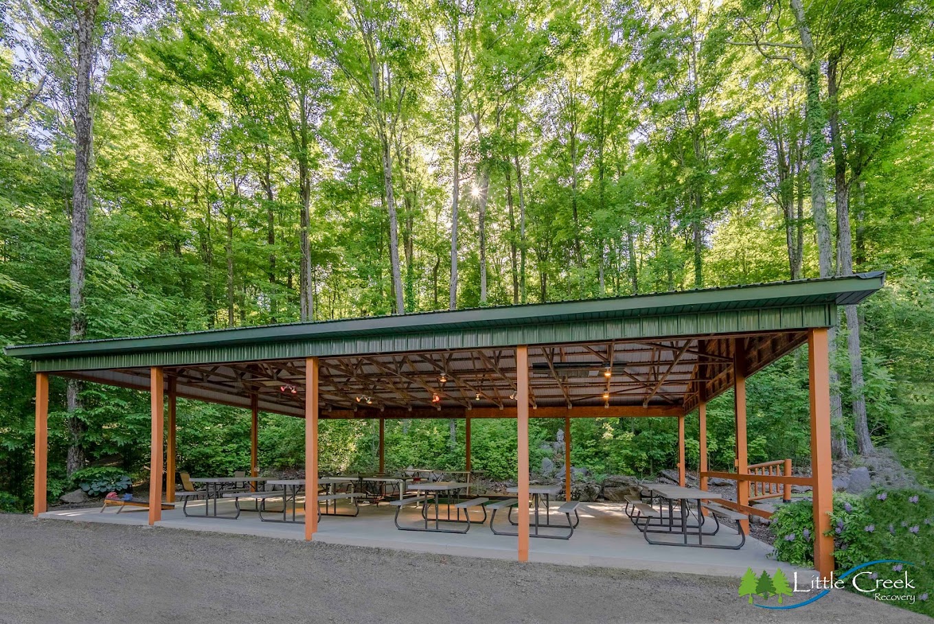 A rustic outdoor pavilion surrounded by lush green trees