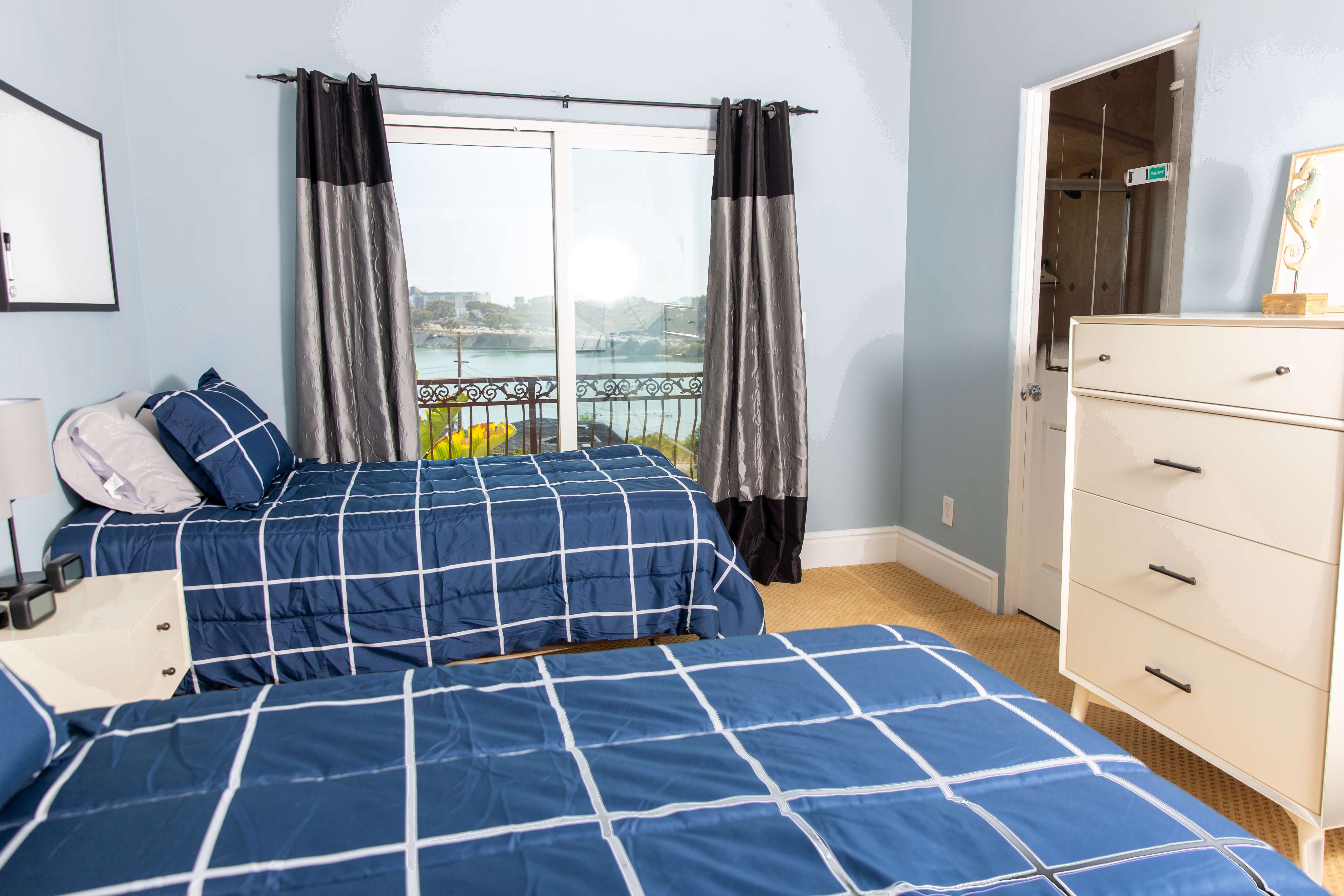 Two twin beds in room with sliding glass doors and ocean view