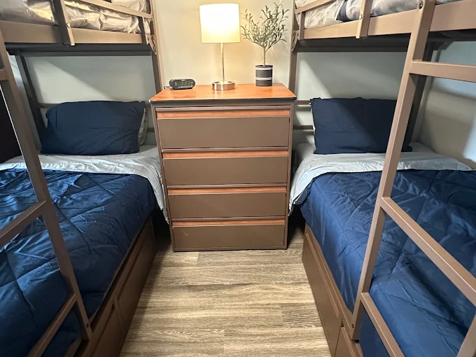 Room with two bunk beds and dresser with lamp