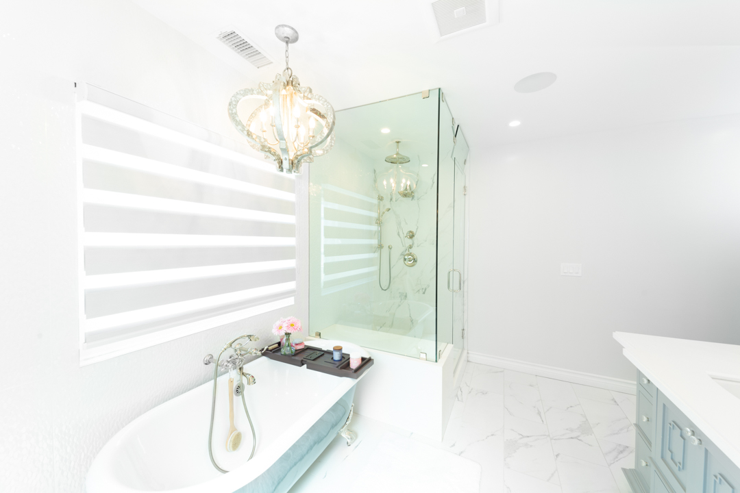 Bright white bathroom with chandelier and glass shower