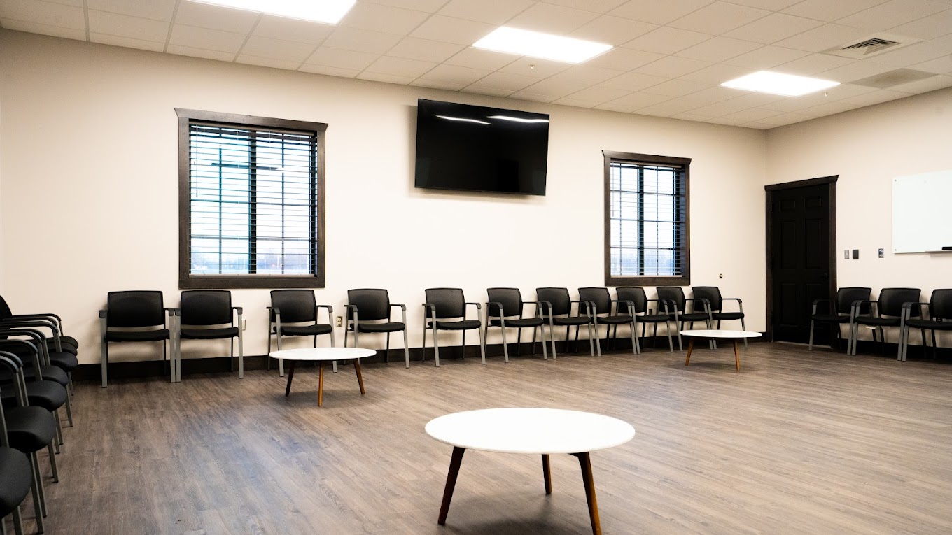  Spacious group therapy room with chairs and large windows.