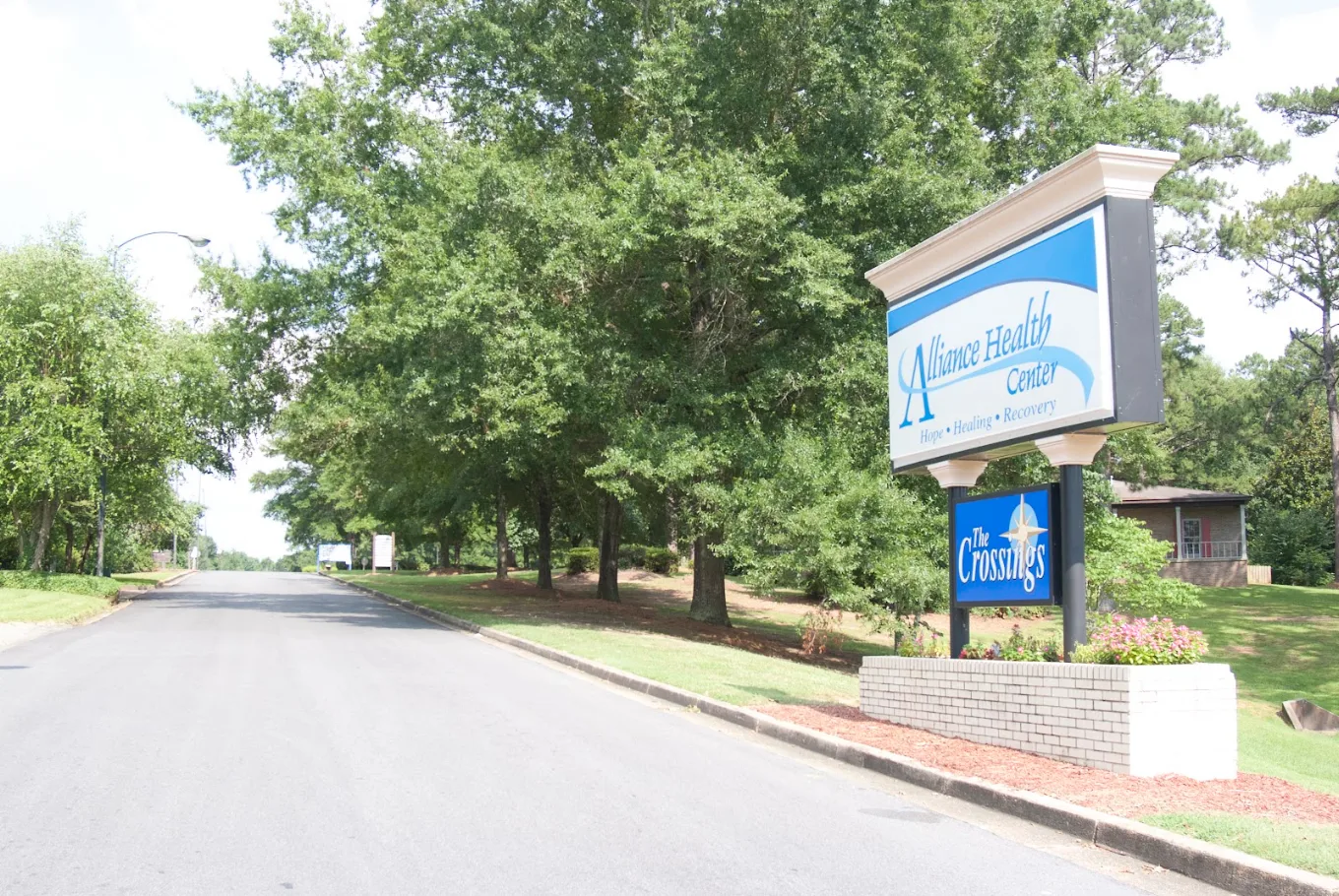 Alliance Health Center sign beside tree-lined entrance road