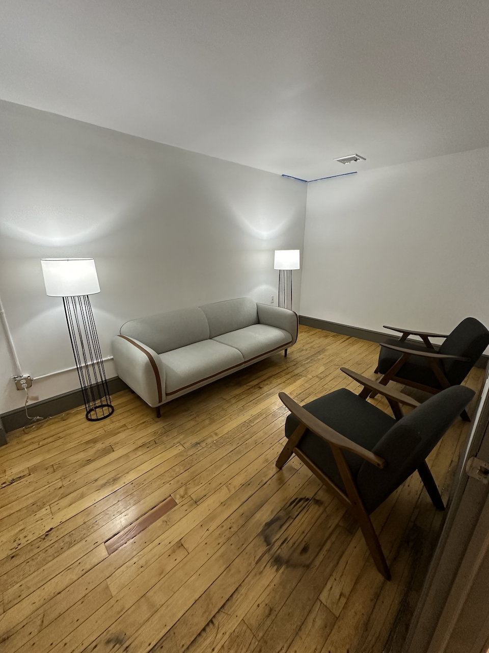 Minimalist therapy room with sofa, chairs, and standing lamps