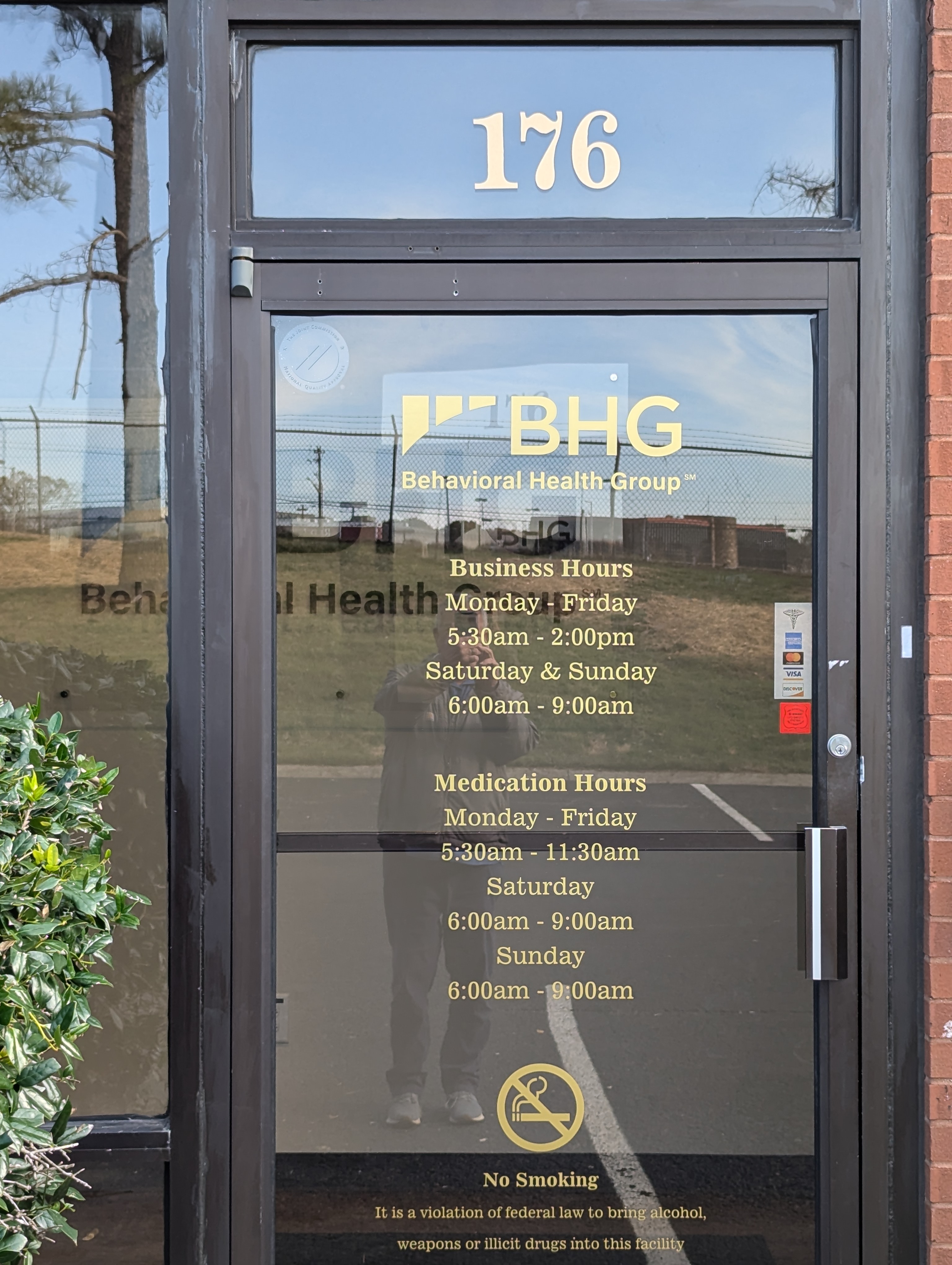 Main entrance door with business hours and BHG signage