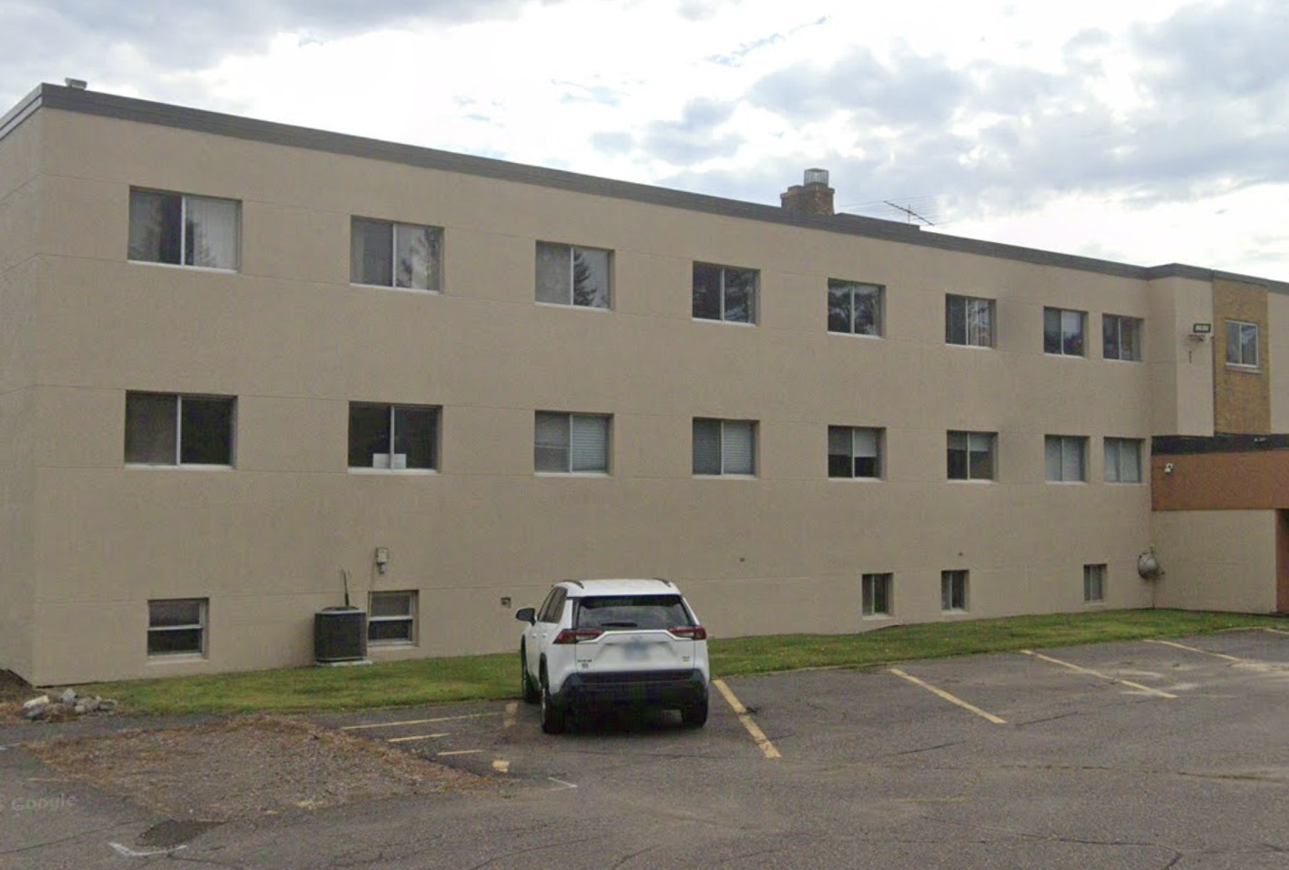 Beige three-story building with windows and parking area