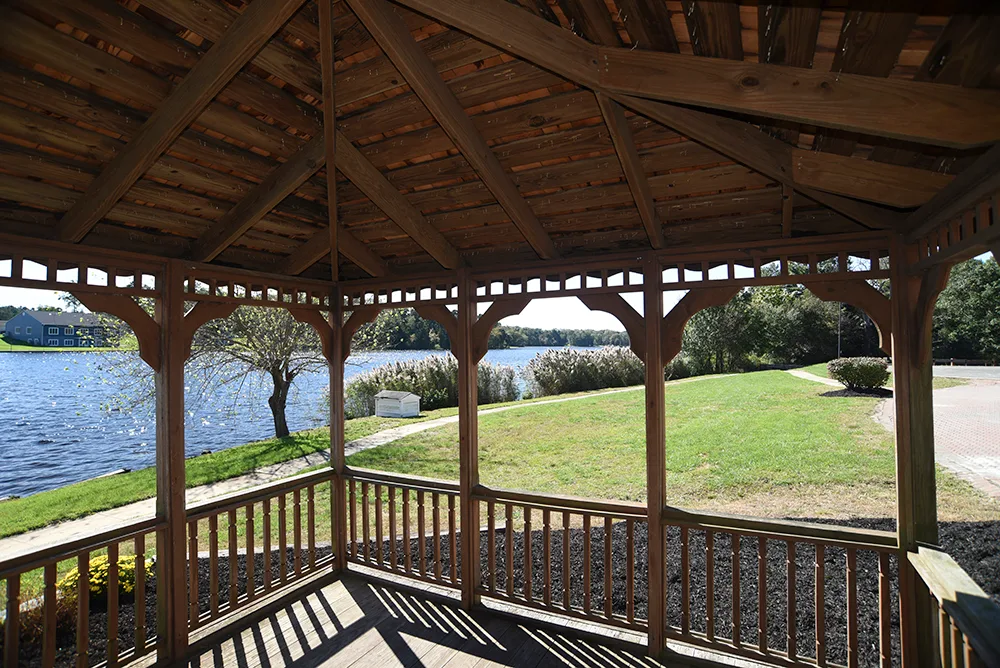 View from wooden gazebo overlooking a lake and grassy lawn